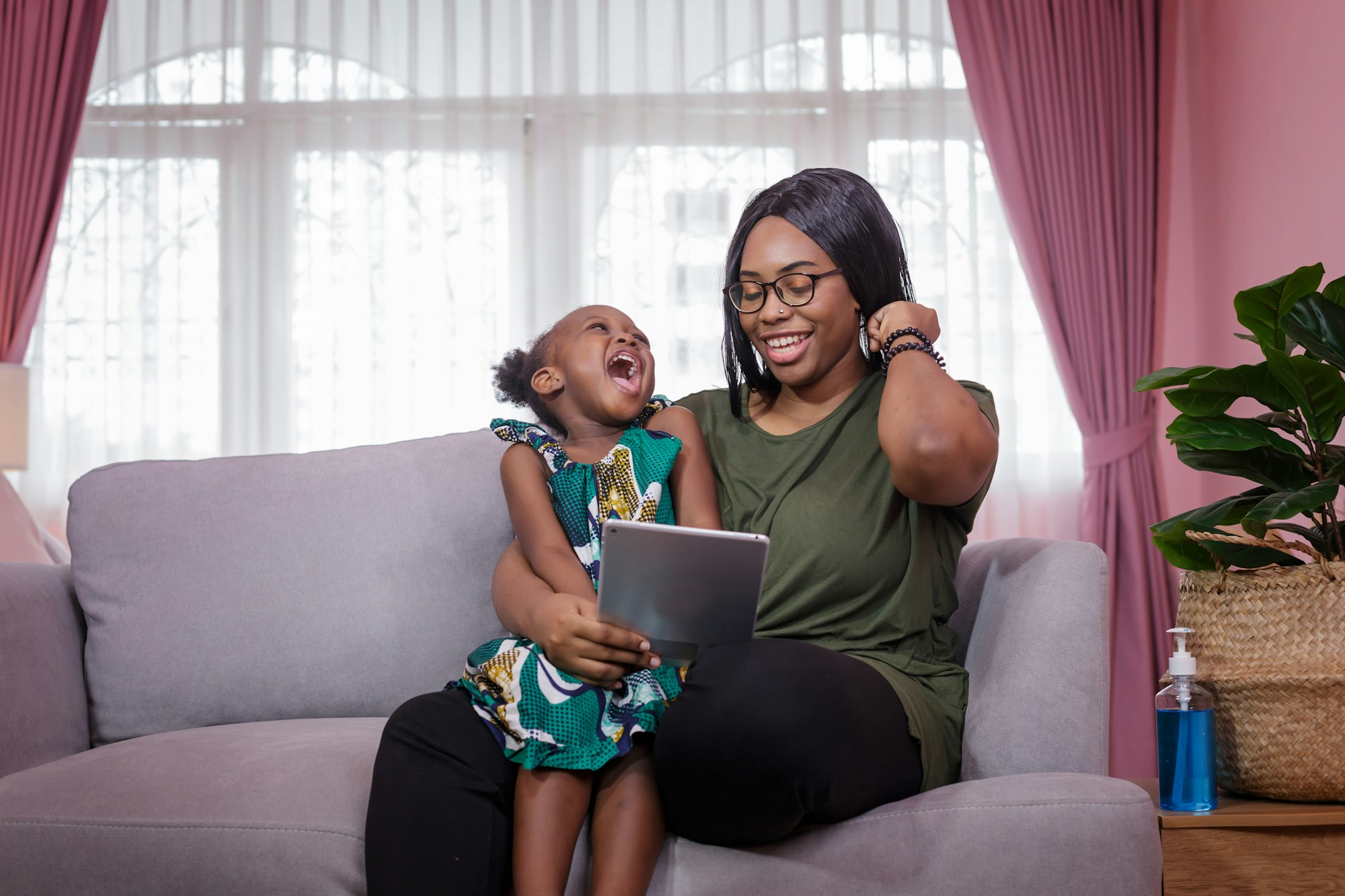 Mom was teaching her girl through tablet joyfully while sitting on the sofa. Home study concept