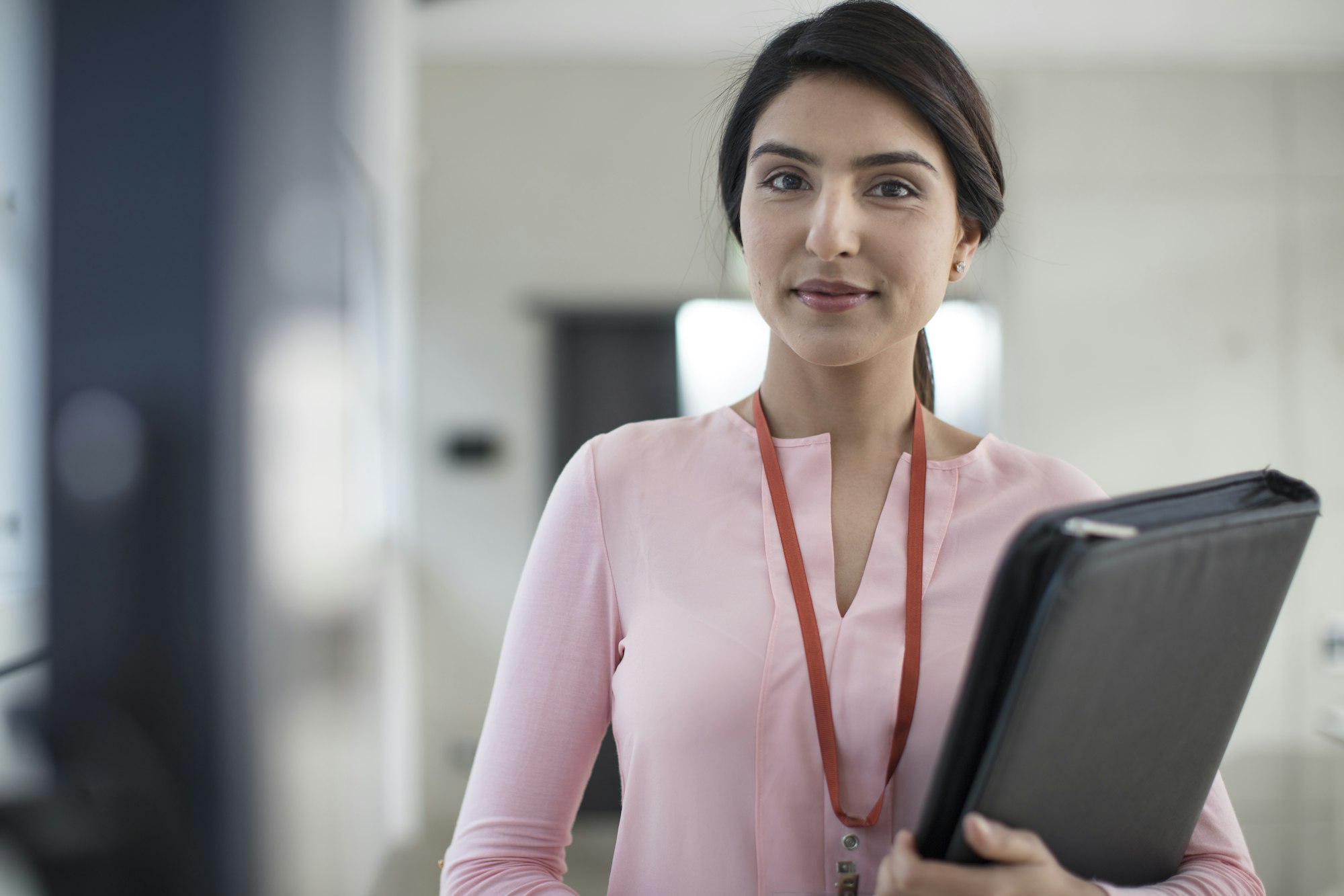 Portrait of young woman holding folder on the corridor in office